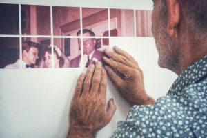 Close up of Doug Winter installing artwork which isa series of squares of a family portrait. 