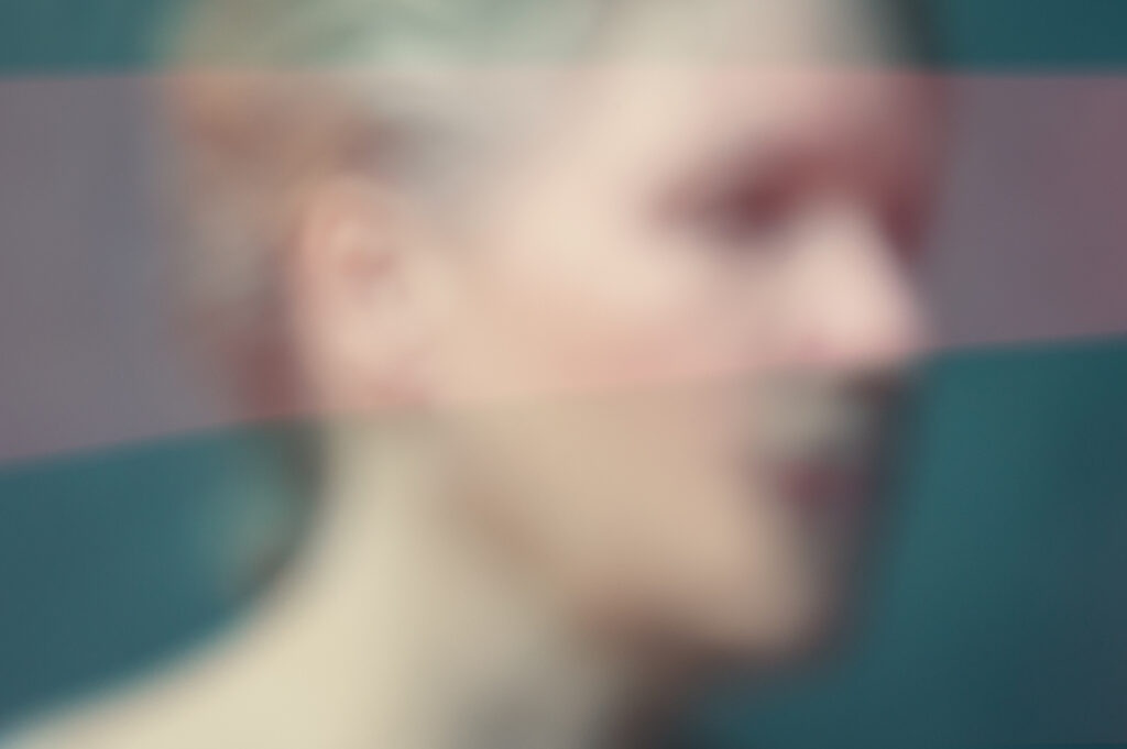 Out of focus image of a woman in profile, cropped to head and shoulders on cyan green background with a wash of light pink running horizontally across the entire image.